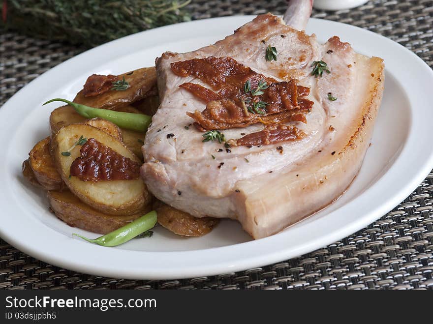 Pork chop with crispy bacon, pan-fried potatoes and green beans