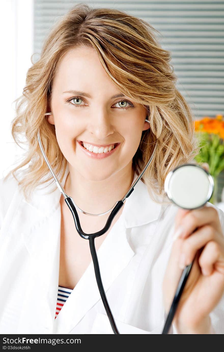 Close-up of beautiful blonde female doctor with stethoscope, smiling at camera. Close-up of beautiful blonde female doctor with stethoscope, smiling at camera