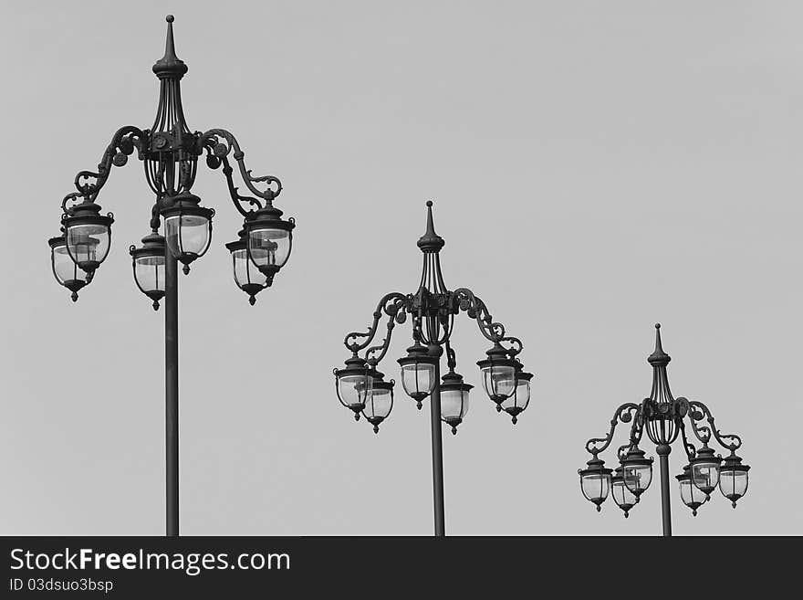 Three vintage lamp posts on light gray sky. Three vintage lamp posts on light gray sky