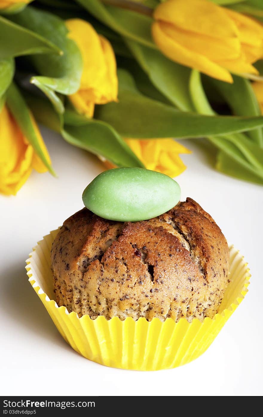 Cupcake and blurred yellow tulips in the background. Cupcake and blurred yellow tulips in the background