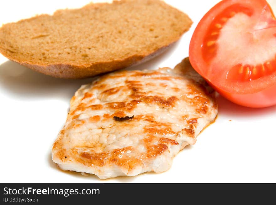 Fried piece of meal with bread and tomato over white. Fried piece of meal with bread and tomato over white