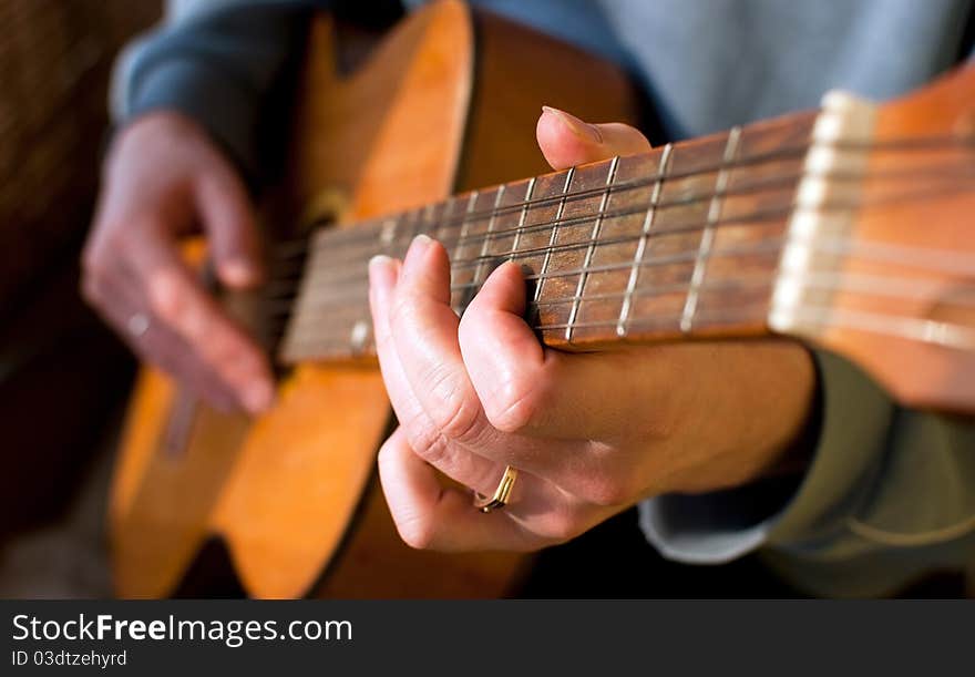 Brown guitar in hands of the guy playing it