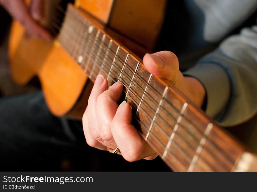 Brown guitar in hands of the guy playing it