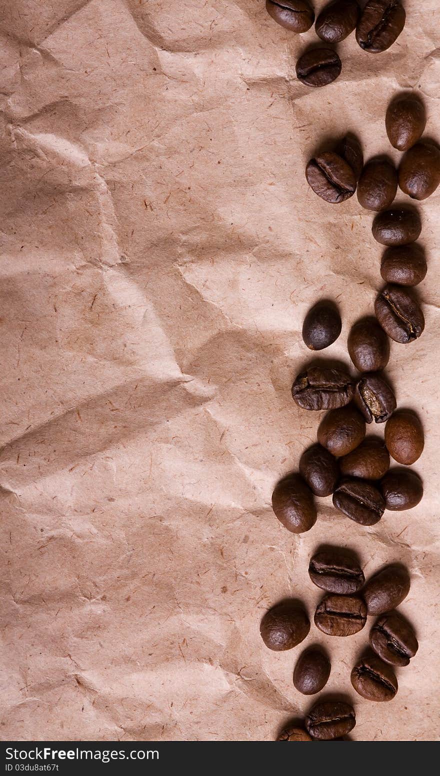 A pile of coffee beans forming a simple stripe frame on a crumpled paper background. A pile of coffee beans forming a simple stripe frame on a crumpled paper background