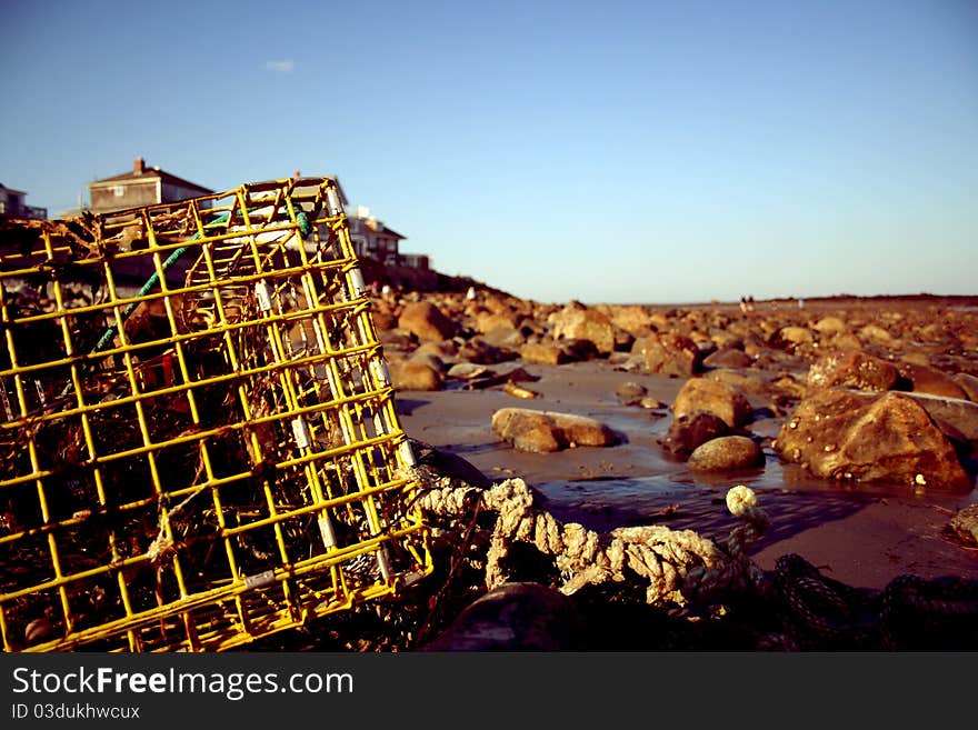 Lobster pot lying on a rock-filled beach at sunset. Lobster pot lying on a rock-filled beach at sunset