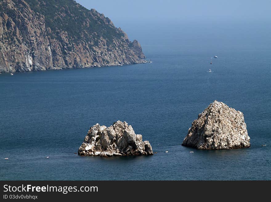 Two old rocks in the sea near mountains