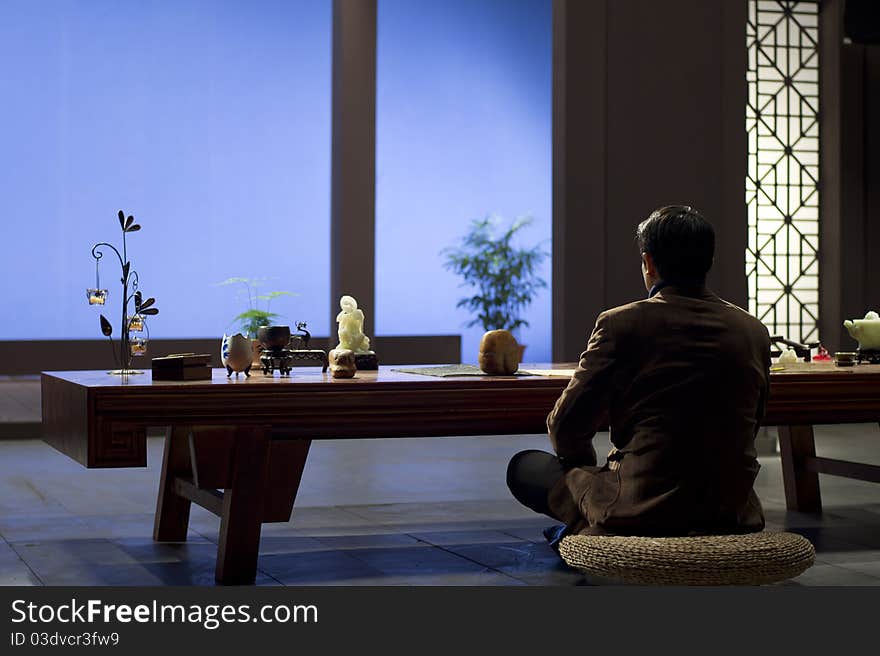 A Chinese meditating before jade on table. A Chinese meditating before jade on table