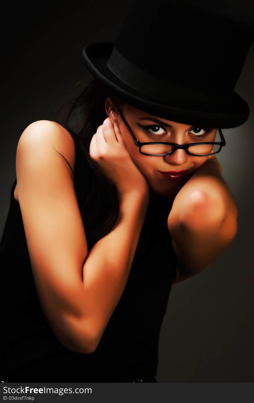 The young woman in a black dress and glasses posing in studio. The young woman in a black dress and glasses posing in studio