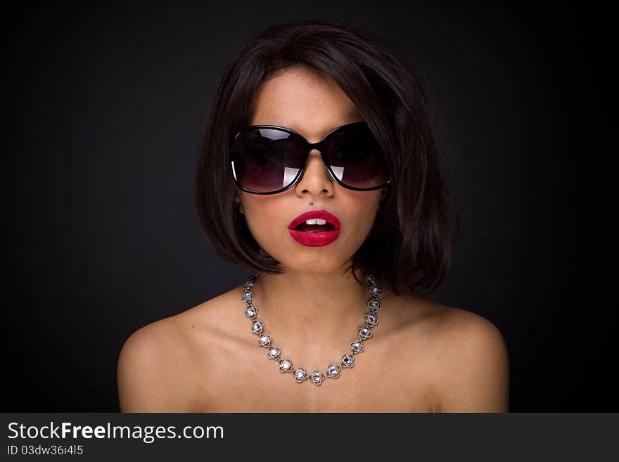 Sexy brunette elegant woman expressed wearing neckles  and sunglasses