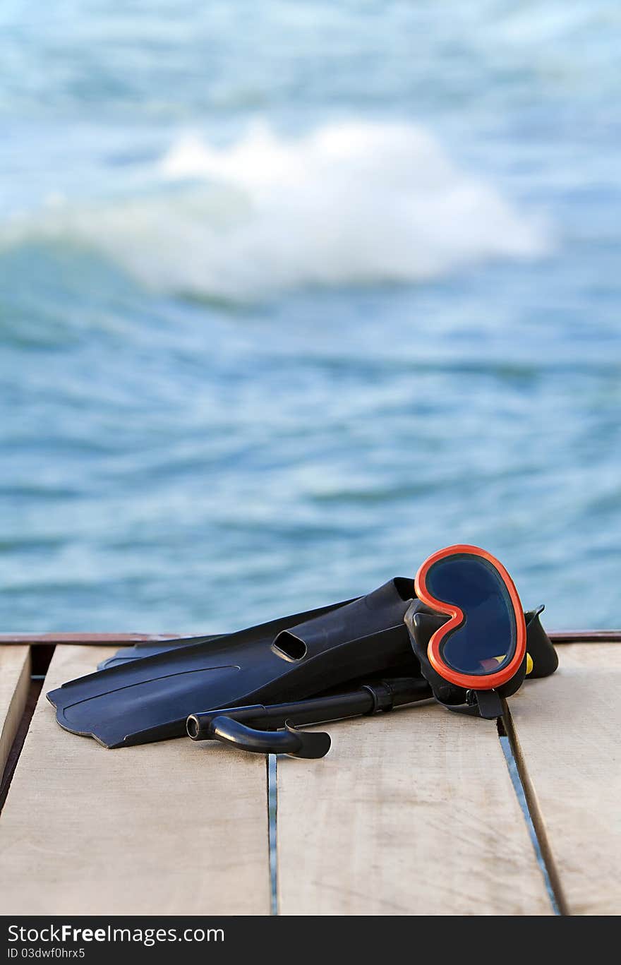 A view of diving goggles, swimming fins and snorkel near the lake. A view of diving goggles, swimming fins and snorkel near the lake