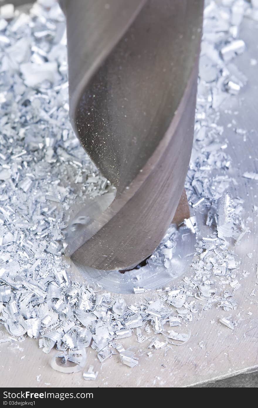 A man drilling a hole in the metallic sheet