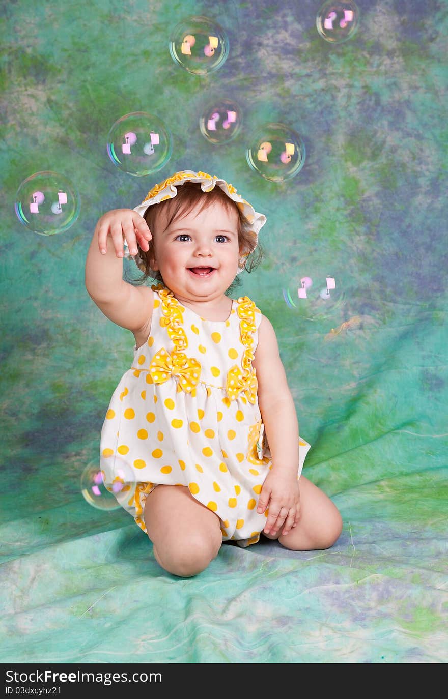 Portrait of the laughing child with soap bubbles on a green background in studio. Portrait of the laughing child with soap bubbles on a green background in studio