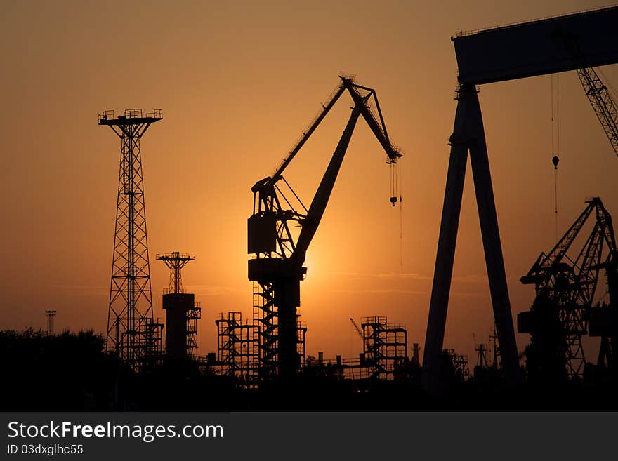 Dark silhouettes of tower cranes against sunset. Dark silhouettes of tower cranes against sunset.