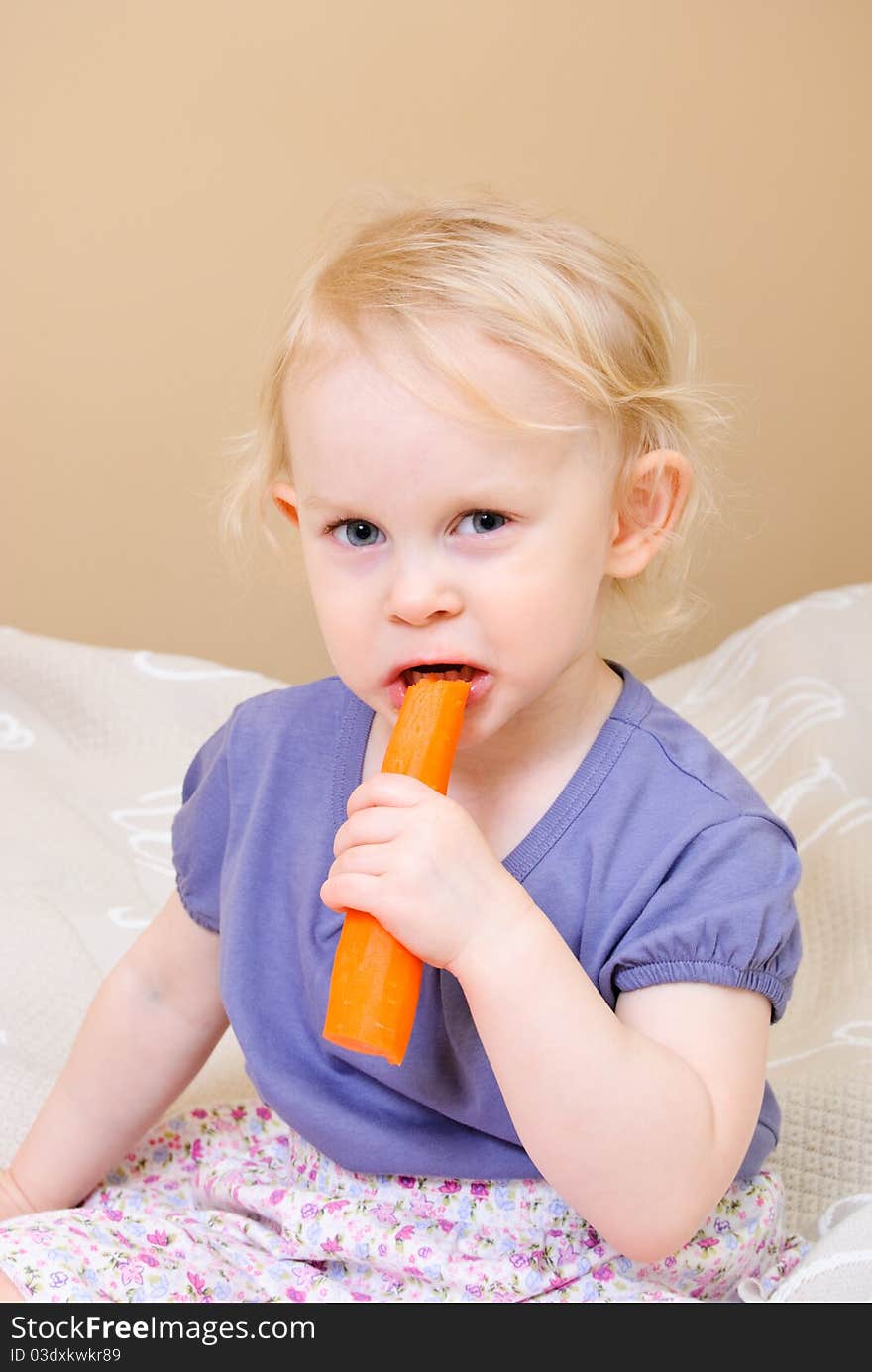 Cute girl eating carrot at home. Cute girl eating carrot at home