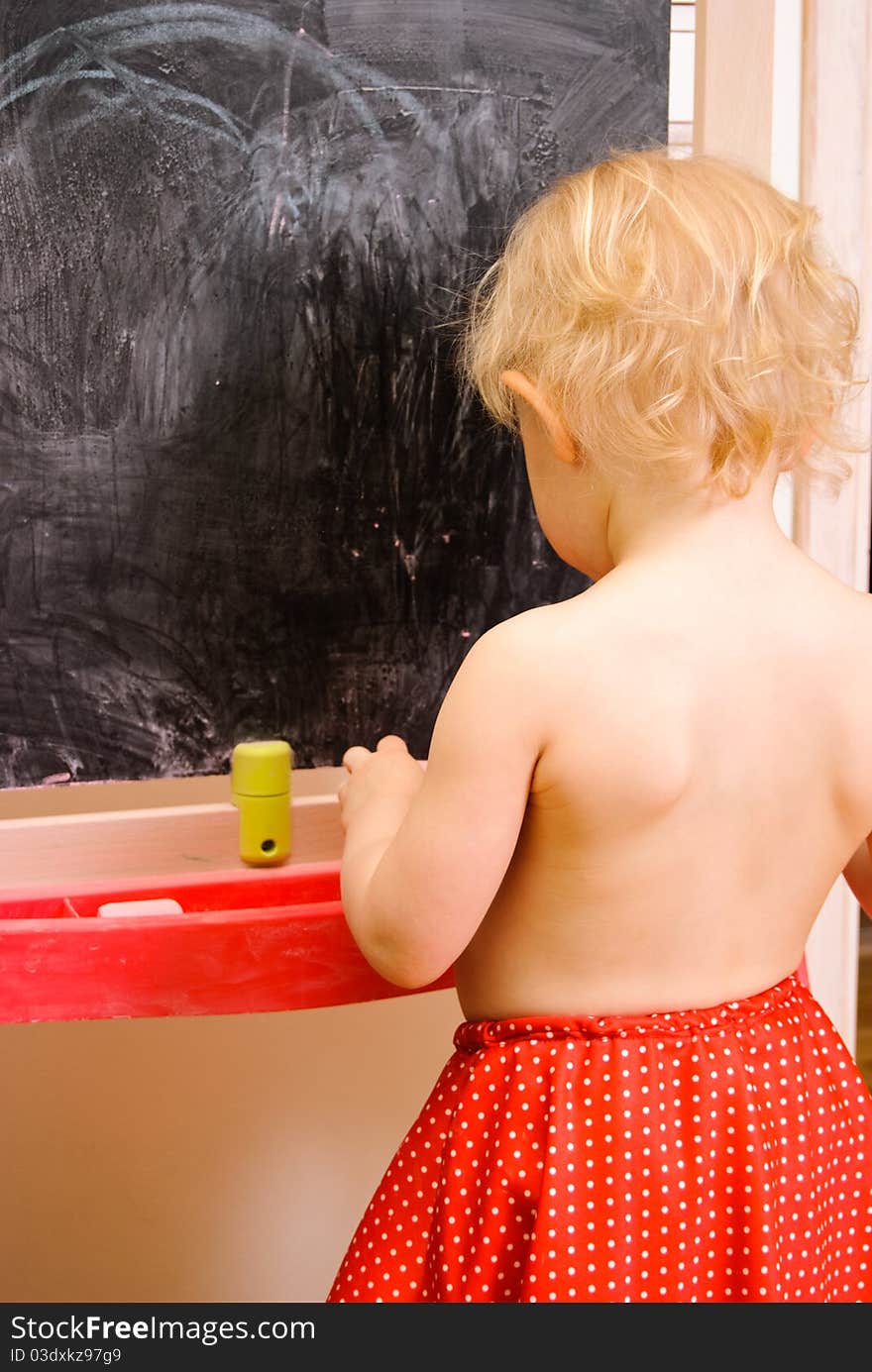 Baby girl drawing on chalkboard