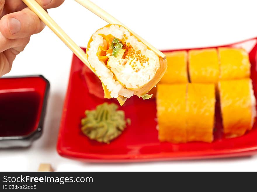 Men's hand holding sushi served on a plate. White background