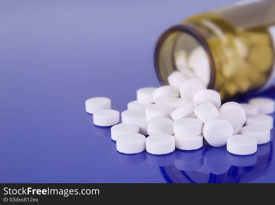 Macro of white pills and a vial