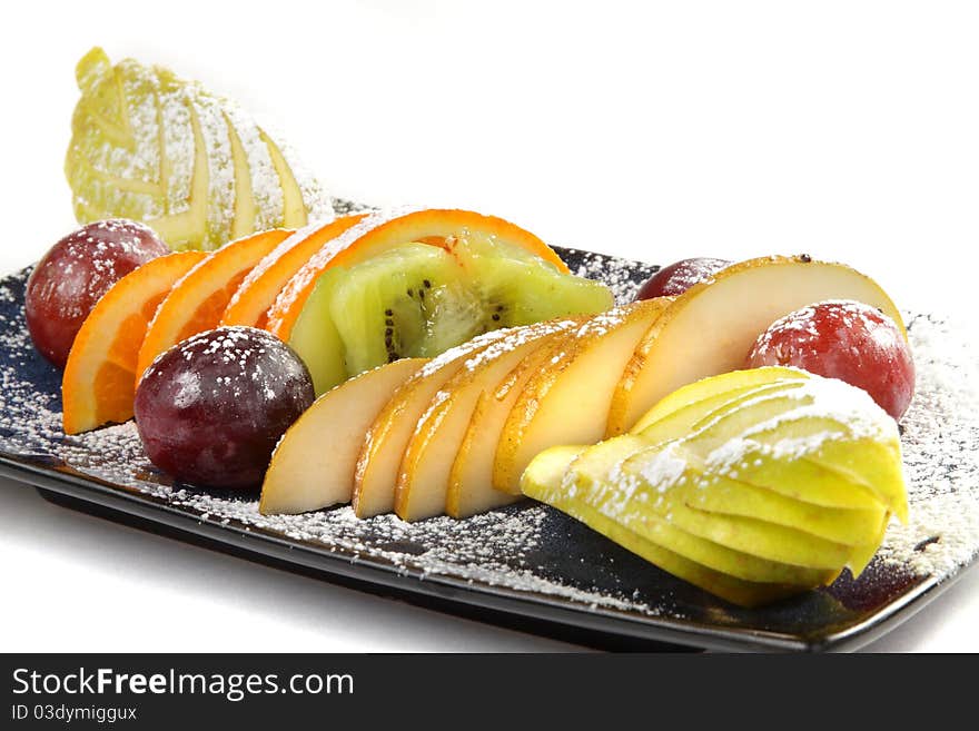 Cutting from different tropical fruit on a black rectangular plate