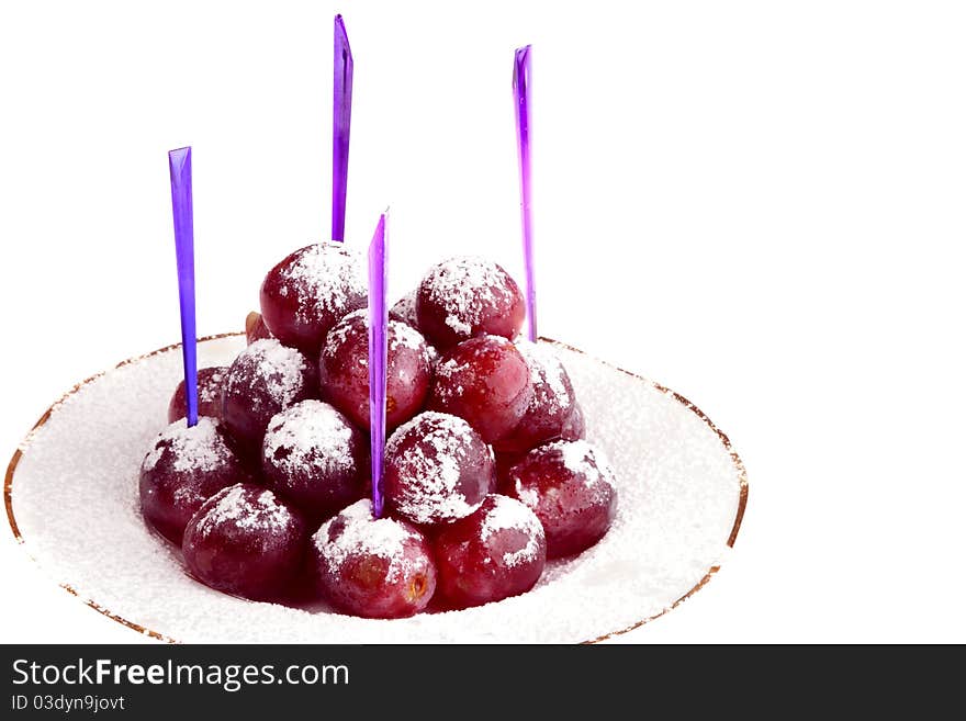 Red grapes on the white plate, strewed by powdered sugar