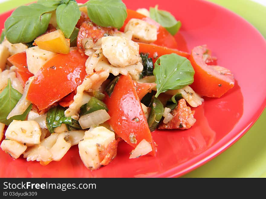 Salad - made of farfalle pasta, tomato, salami, bell pepper and mozzarella, decorated with basil