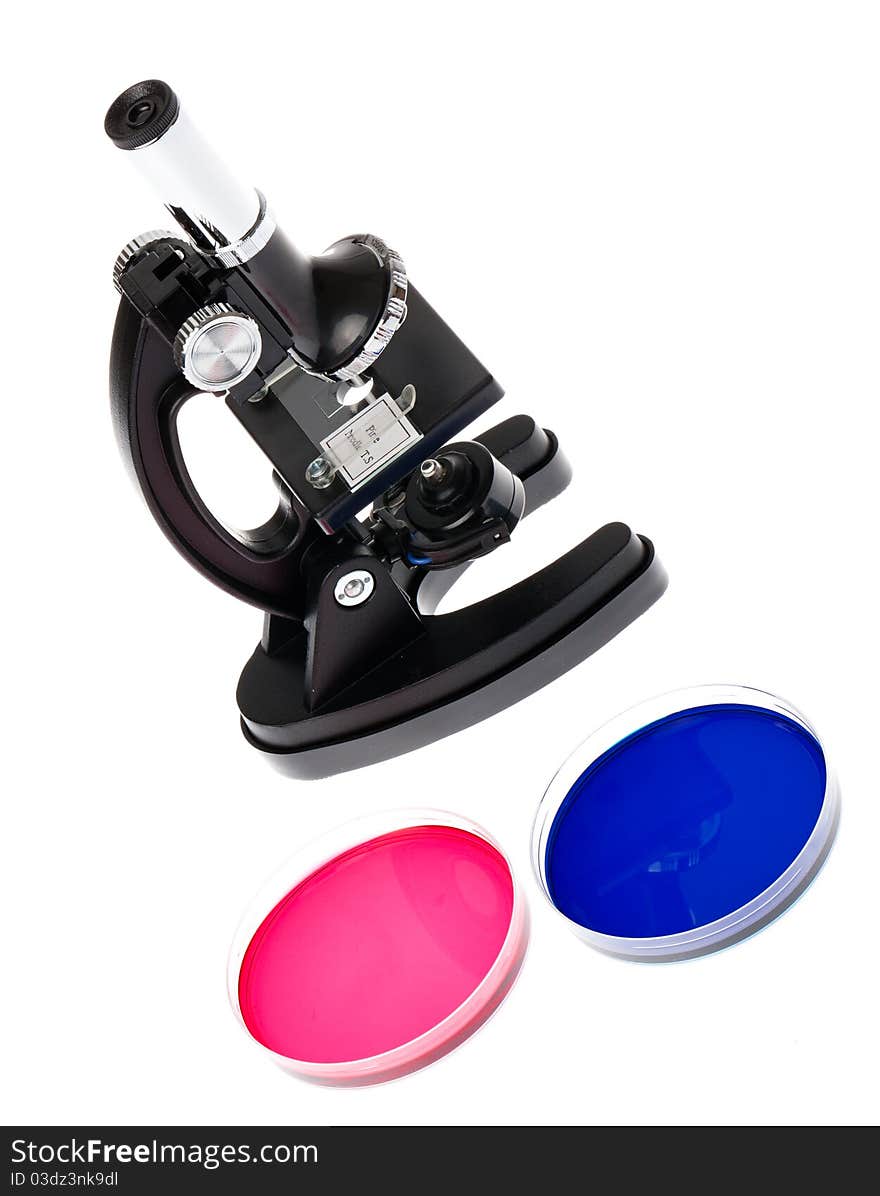 A microscope with two petri dishes containing bright red and blue liquids. A microscope with two petri dishes containing bright red and blue liquids