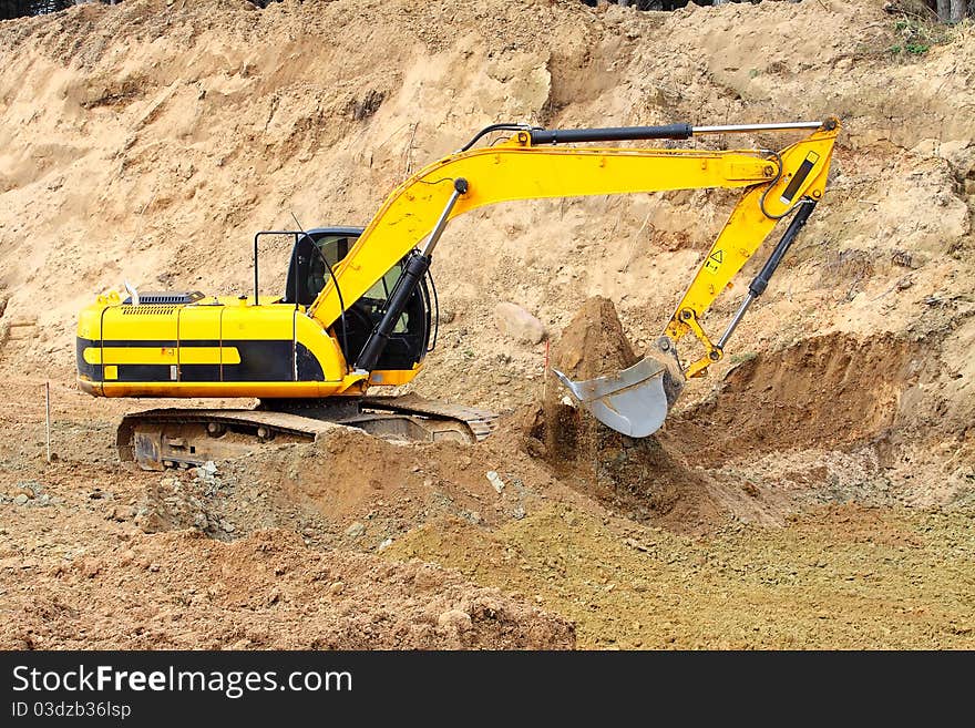 Old dredge digging the earth, photographed against the earth, the blue sky and a green bush