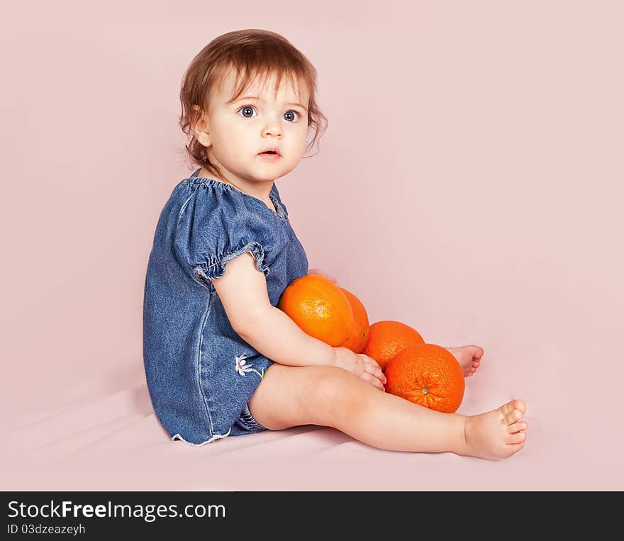 Portrait of the child with oranges on a pink background in studio. Portrait of the child with oranges on a pink background in studio