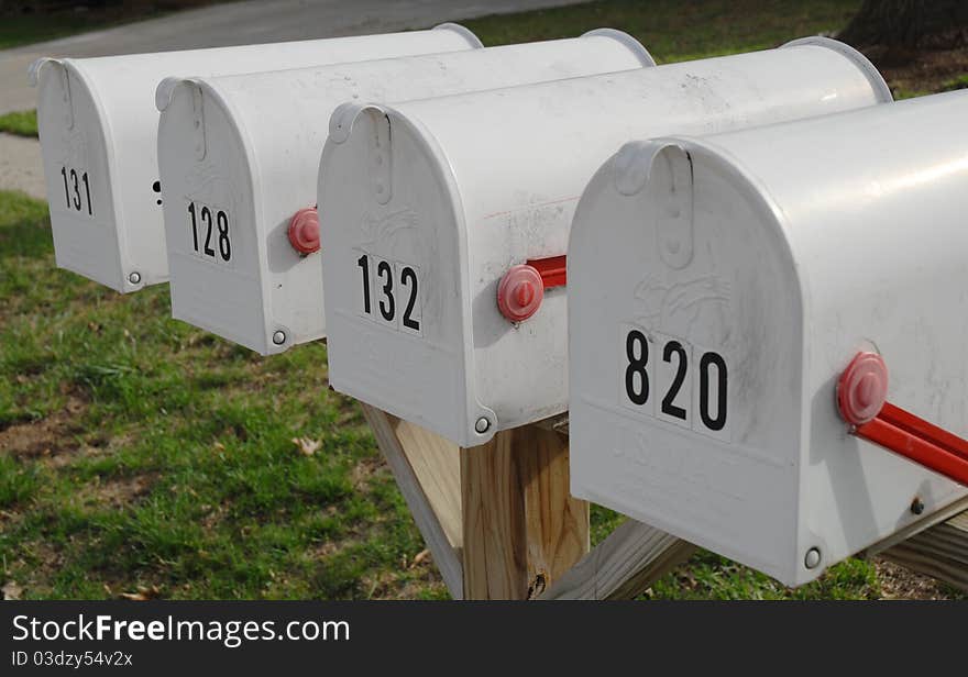 White mailboxes on a wooden post with closed doors and red flags that are in the down position. White mailboxes on a wooden post with closed doors and red flags that are in the down position.