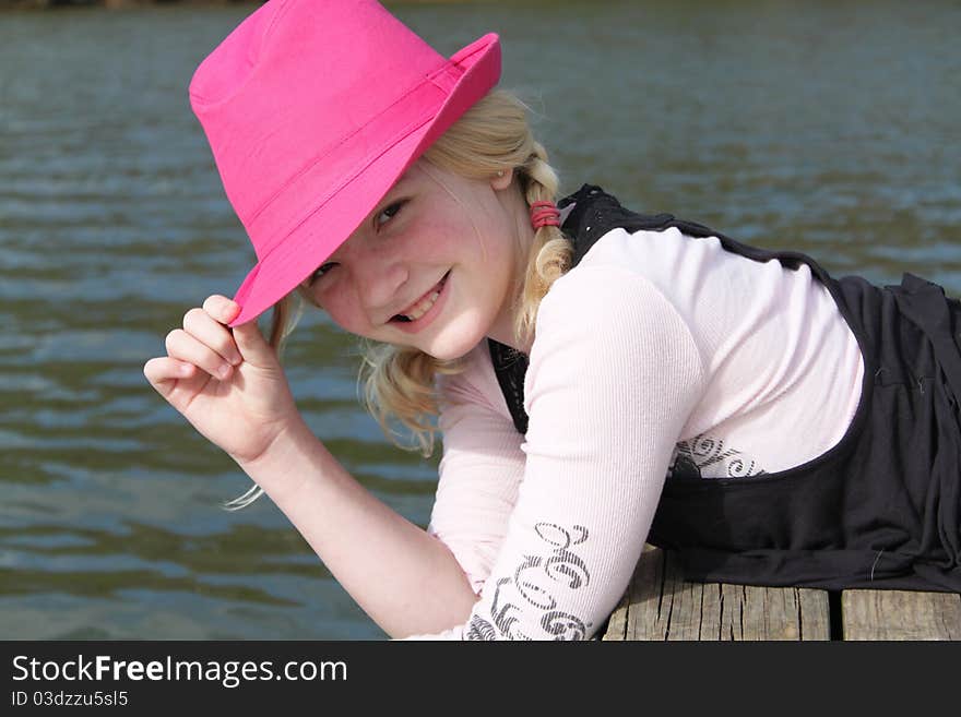 Young girl with a pink hat posing on the dock. Young girl with a pink hat posing on the dock.