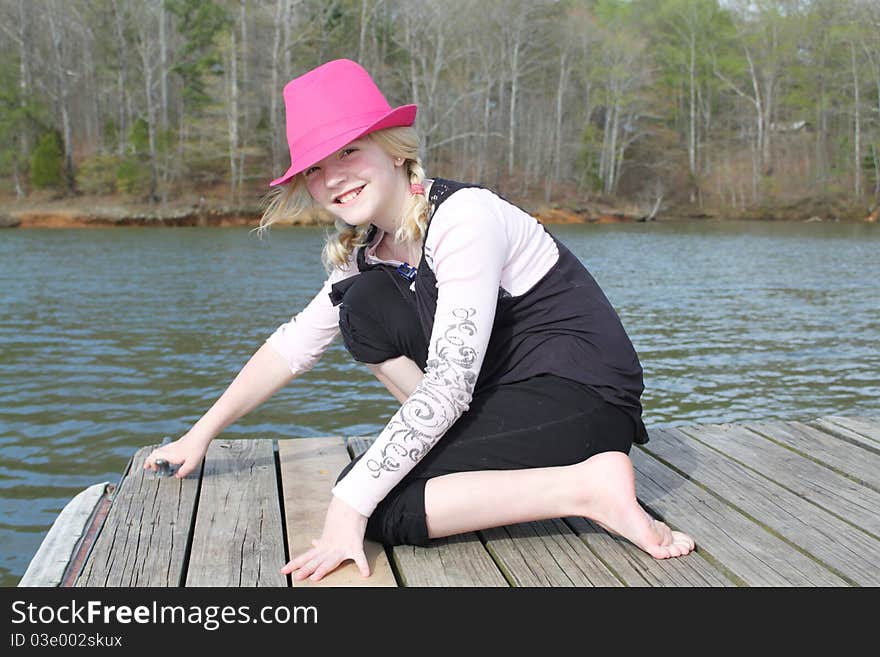 Girl in a pink hat on a wooden dock. Girl in a pink hat on a wooden dock.