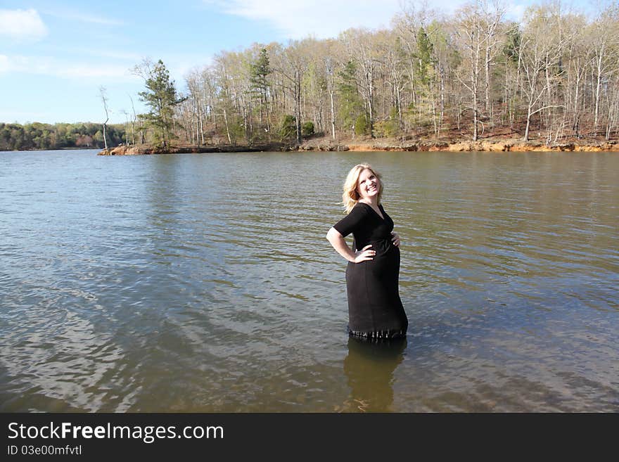 Beautiful pregnant woman standing in the water in a natural setting. Beautiful pregnant woman standing in the water in a natural setting.