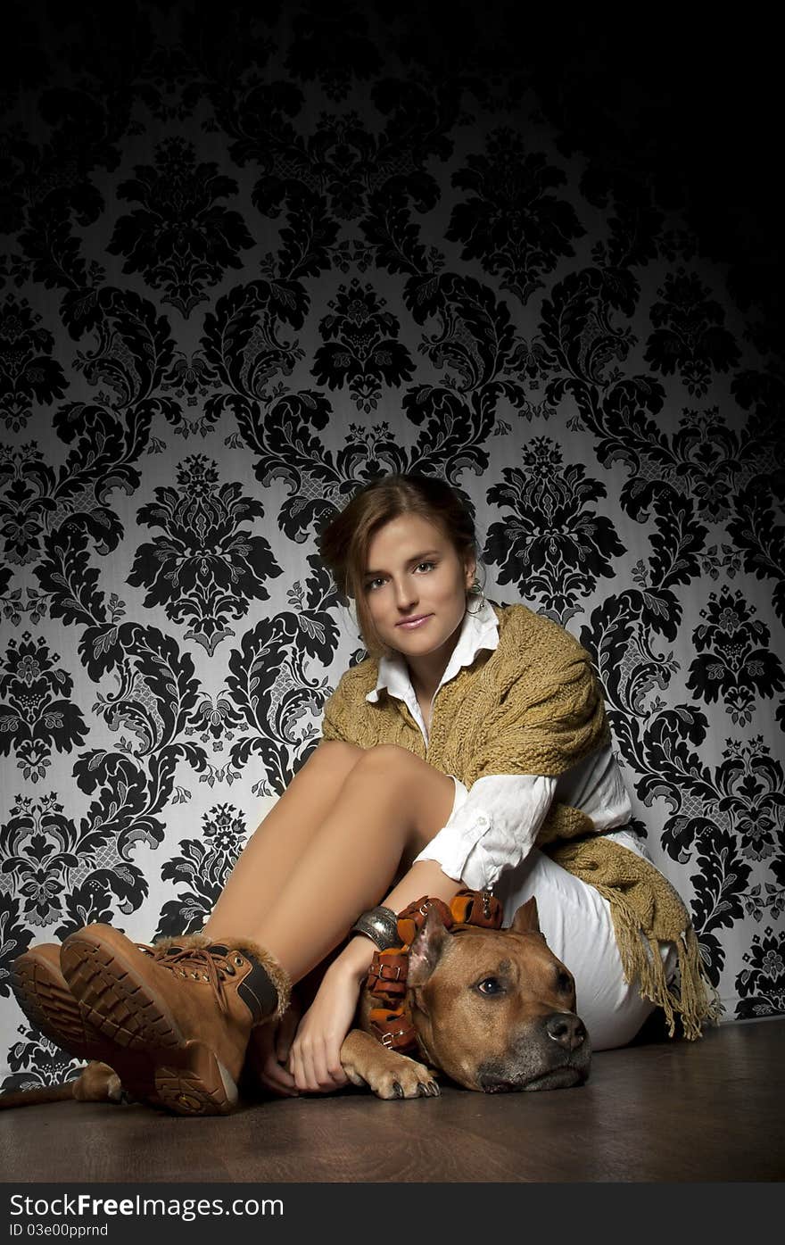 Young and beautiful girl  with American Staffordshire Terrier sitting on brown floor. Young and beautiful girl  with American Staffordshire Terrier sitting on brown floor