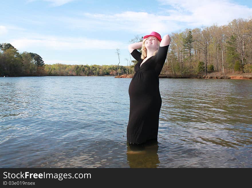 Happy pregnant woman standing in water at the edge of a beautiful lake. Happy pregnant woman standing in water at the edge of a beautiful lake.