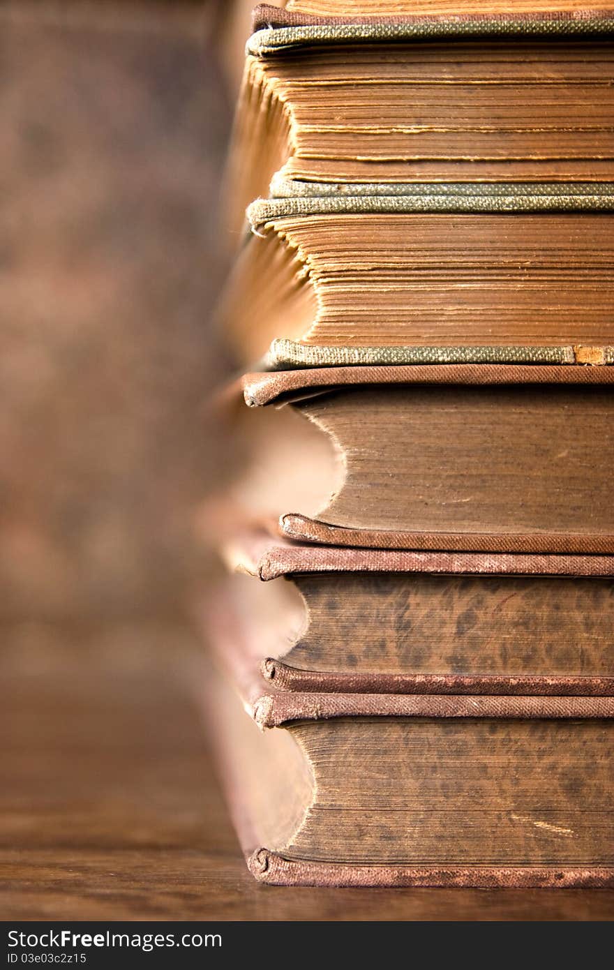 Stack of antique aged books on wooden table and background with interesting texture on butts. Stack of antique aged books on wooden table and background with interesting texture on butts