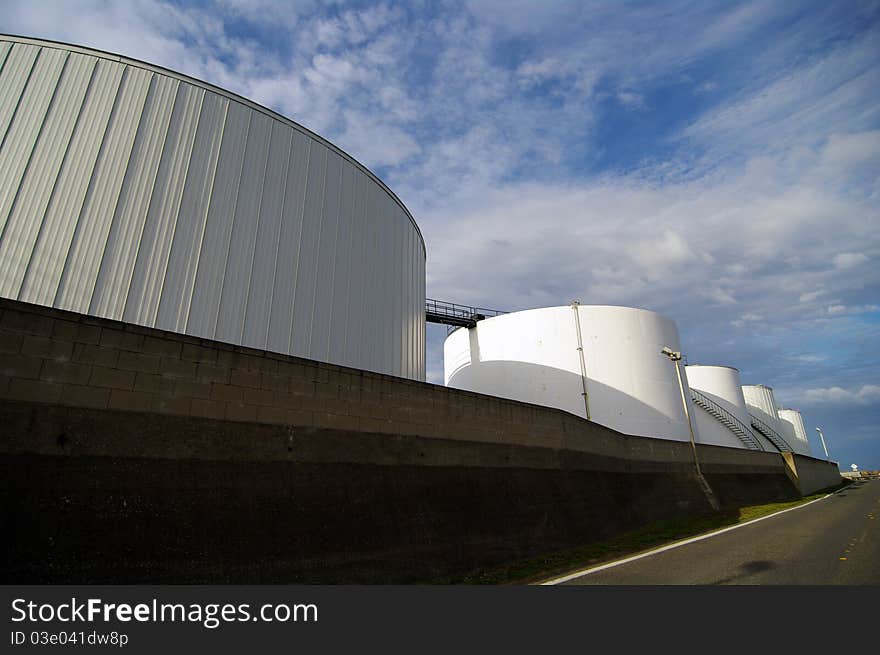 Large white oil holding tanks lined up in a row. Large white oil holding tanks lined up in a row.