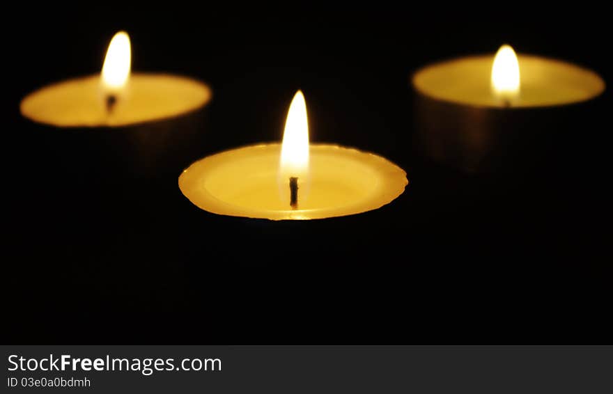 Three memorial candles in darkness