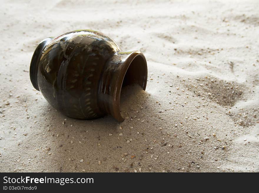 An old pot, covered with sand. An old pot, covered with sand