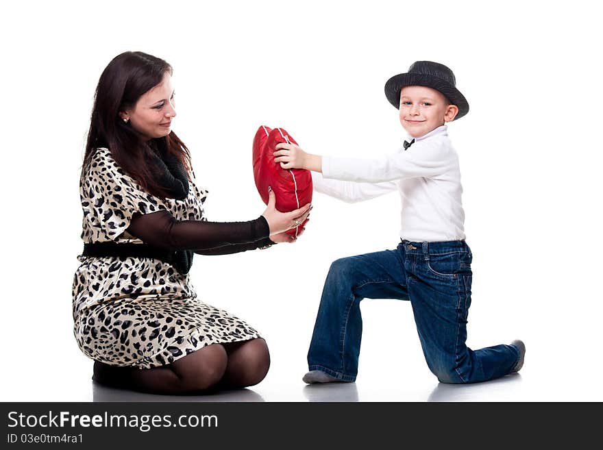 Cute boy giving red heart to his mother isolated on white