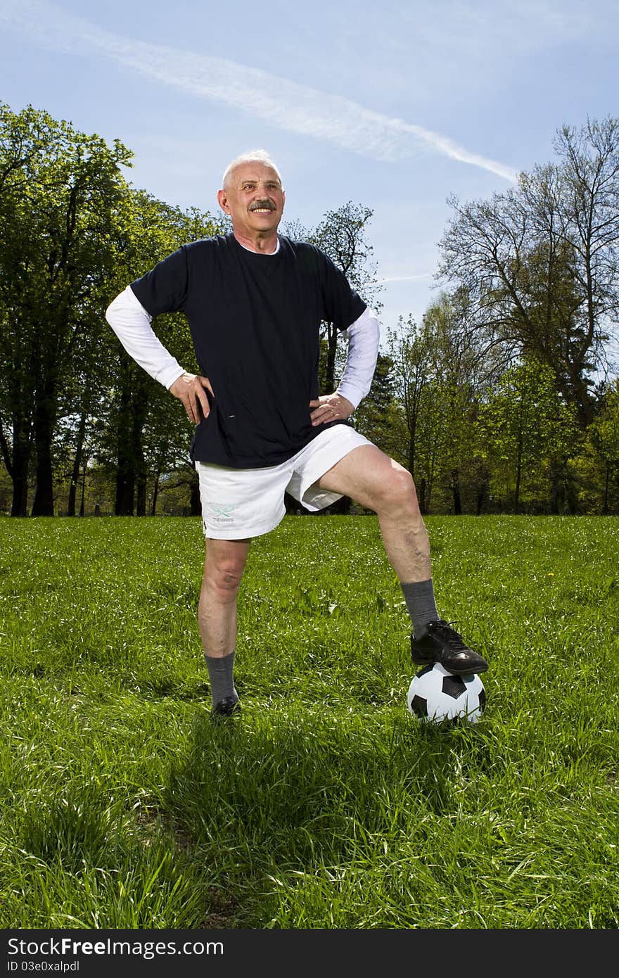 Senior football soccer player in the park standing on the soccer ball