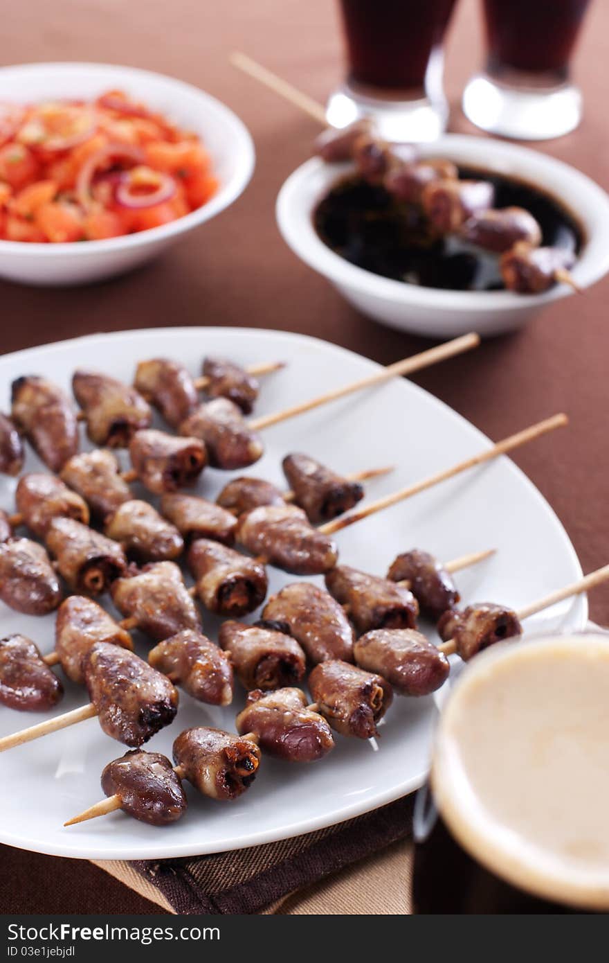 Grilled chicken hearts on skewers with soy sauce, salad and beer