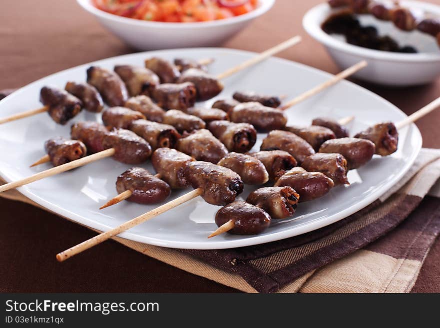 Grilled chicken hearts on skewers with soy sauce and salad.