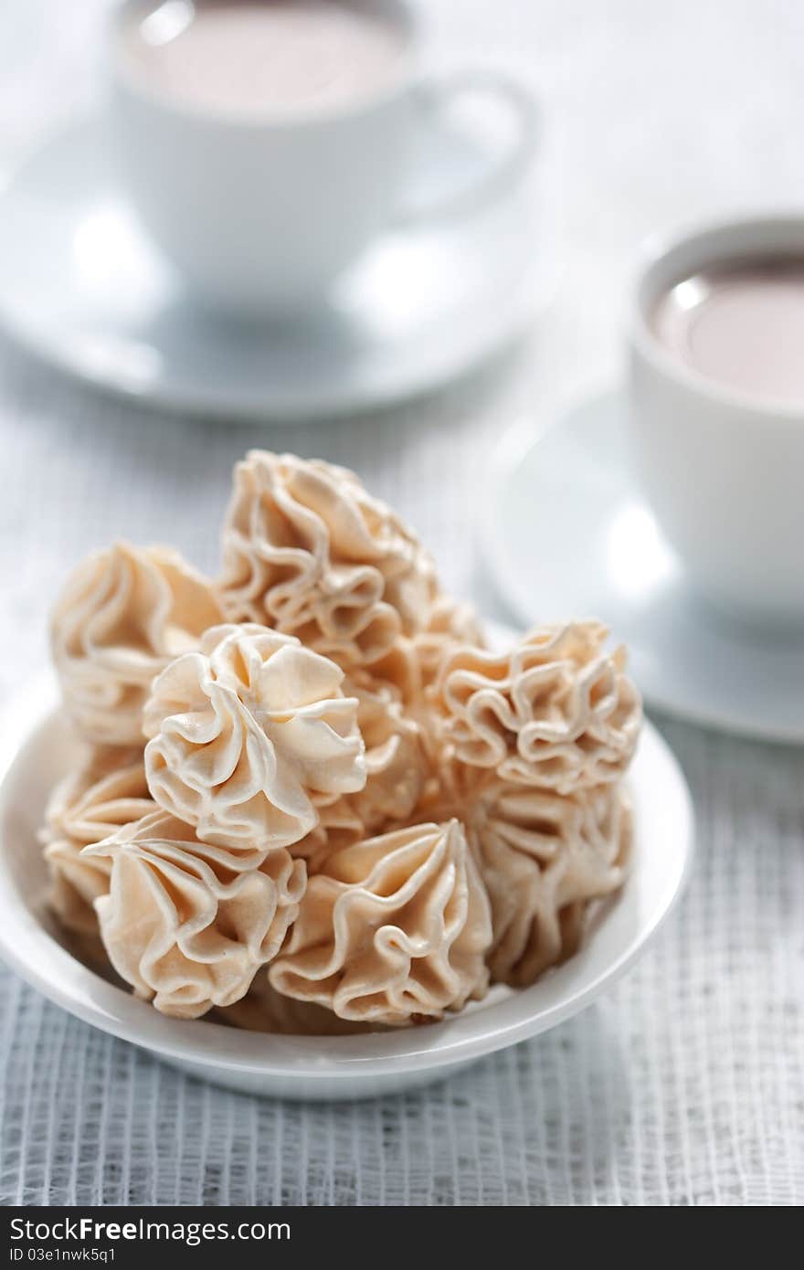 Meringues and two cups of chocolate drink, shallow dof.