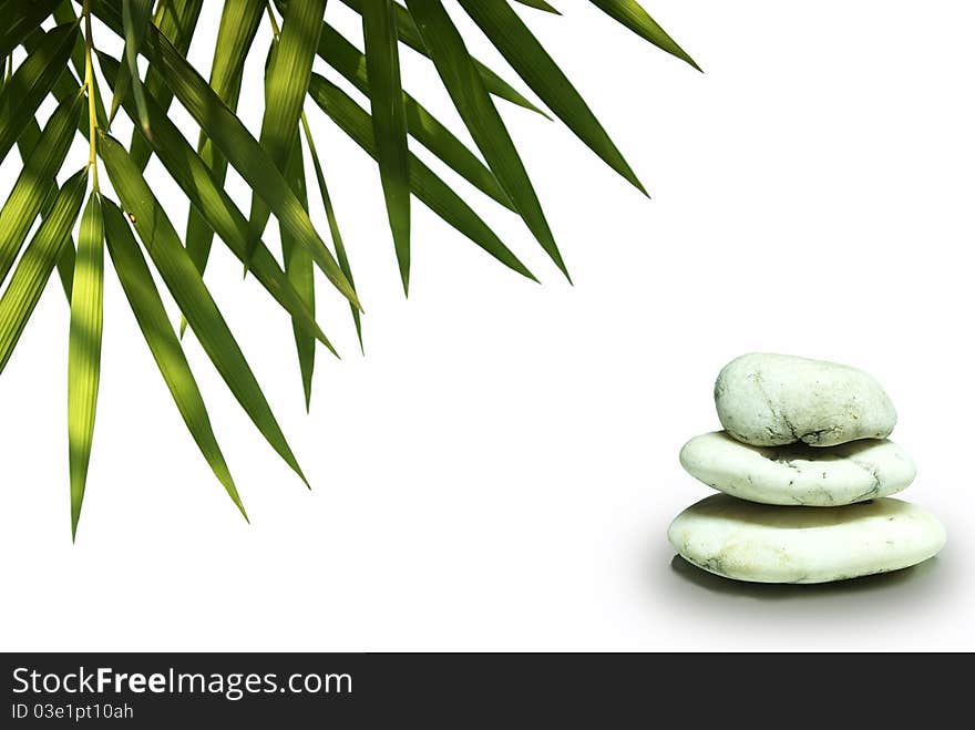 Stones pyramid on white background, green leaves b