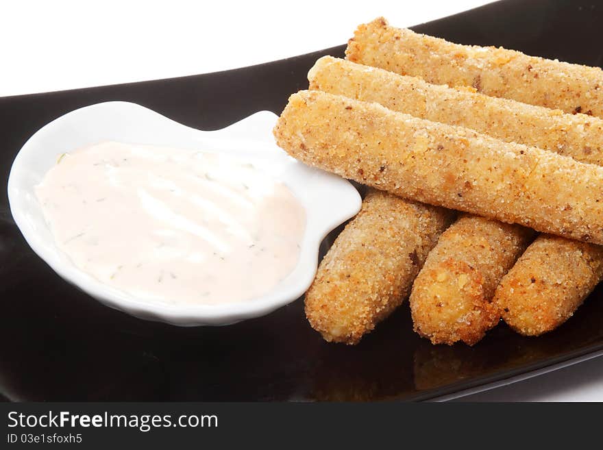 The roasted meat sticks on a black rectangular dish with white sauce