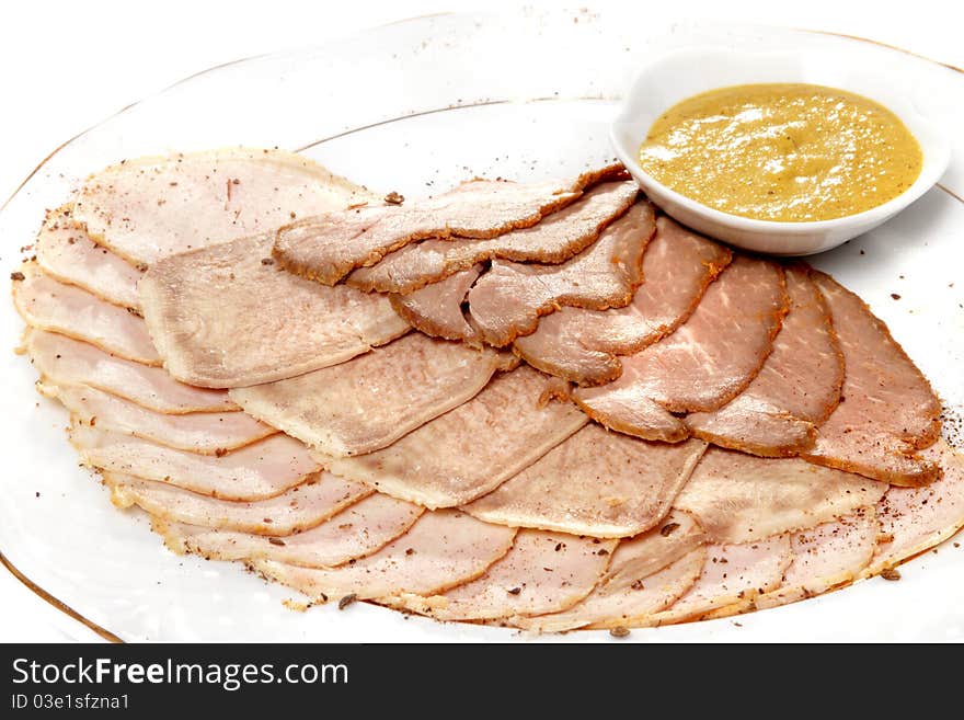 Some grades of cold meat with mustard sauce on a flat white plate