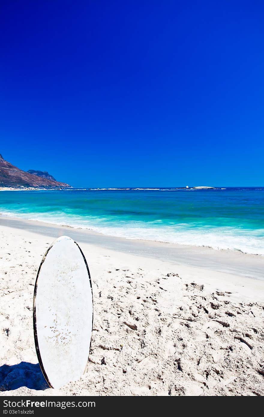 White skim board standing on the beach.