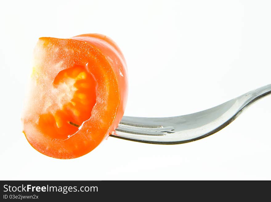 A Tomato on a fork with a white background