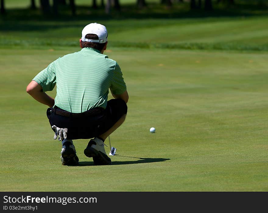 Golfer lines up his putt on the green as he prepares to putt.