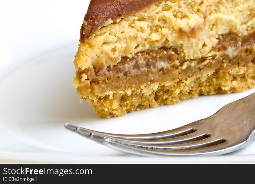 Chocolate Caramel Cheesecake on plate with fork isolated on white.