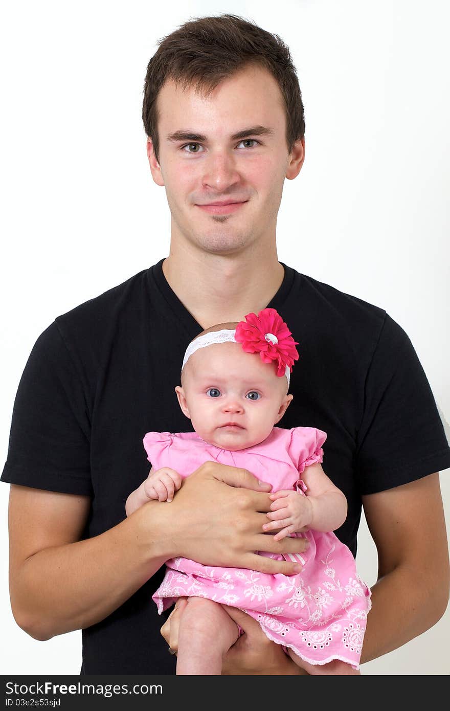 Proud father holding his infant daughter in his arms while baby looks at camera all pretty and dressed in pink